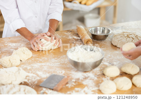 Hands shaping dough in a professional bakery setting 121248950