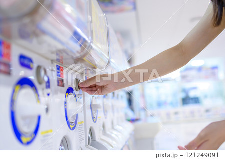 カプセルトイを回す若い女性　ガチャ　 121249091