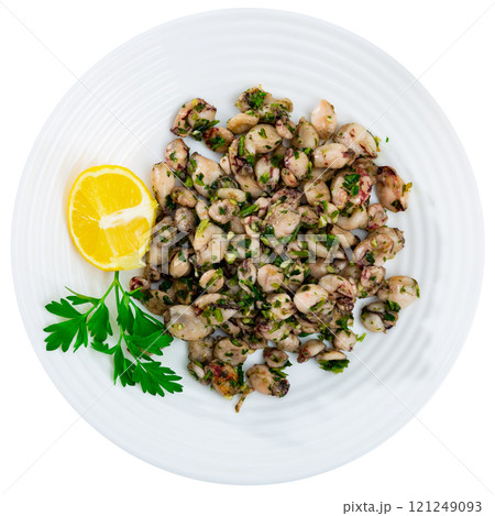 There are pieces of grilled squid on plate. Seafood is complemented with lemon and parsley 121249093