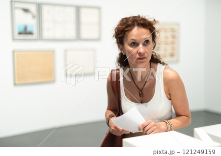 Woman observing photographs on display in photo gallery 121249159