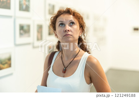 Woman observing photographs on display in photo gallery 121249188