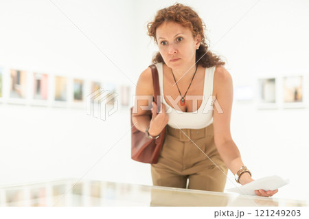 Woman observing photographs in gallery display case Woman observing photographs in gallery display case 121249203
