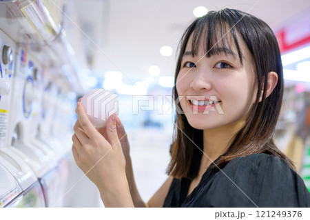 カプセルトイを回す若い女性 ガチャ  カプセルトイを回す若い女性 ガチャ  121249376