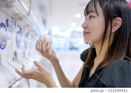 カプセルトイを回す若い女性　ガチャ　 121249381
