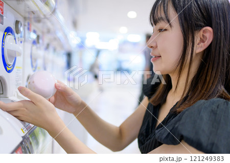カプセルトイを回す若い女性　ガチャ　 121249383