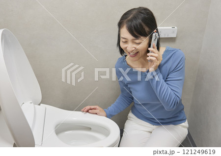 トイレで修理業者に電話をする女性 トイレで修理業者に電話をする女性 121249619