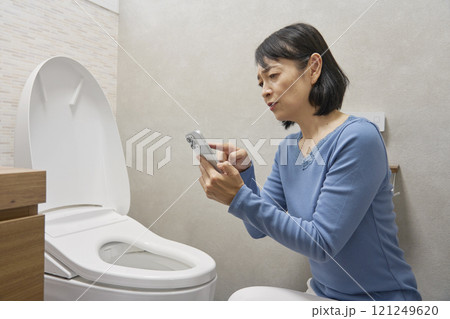 トイレでスマホで修理業者を調べる女性 121249620
