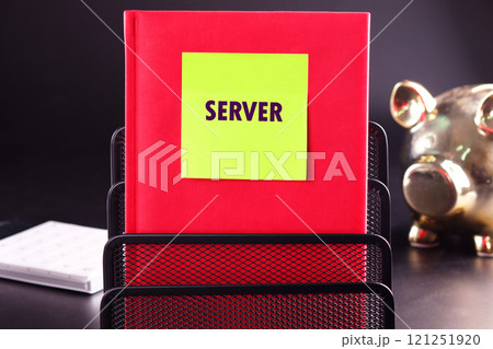 Notebook labeled Server sits in a black metal organizer with a piggy bank in background during office hours Notebook labeled Server sits in a black metal organizer with a piggy bank in background during office hours 121251920