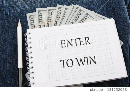 The concept of technology and development. Phrase, word, text ENTER TO WIN on a blank sheet of notepad against the background of dollar bills 121252028