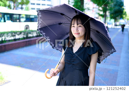 都市部の街中で日傘を差して歩く女性 都市部の街中で日傘を差して歩く女性 121252402