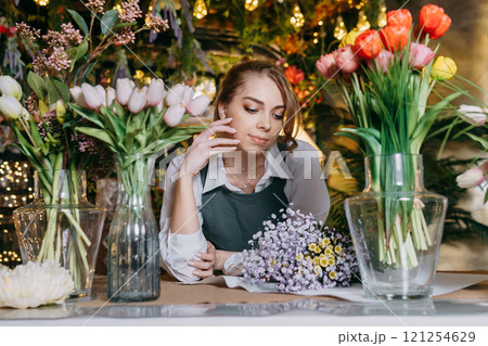 A woman in her florist shop collects bouquets of flowers. The concept of a small business. Bouquets of tulips for the holiday on March 8. A woman in her florist shop collects bouquets of flowers. The concept of a small business. Bouquets of tulips for the holiday on March 8. 121254629