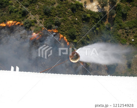Firefighting Helicopter Dumps Buckets of Water to Extinguish a Forest Fire 121254928