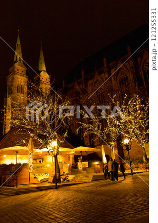 Illuminated Nuremberg at night. Illuminated church of St. Sebald and sidewalk cafe with trees. Old town of Nuremberg at night. Medieval street in the evening. Ancient cathedral in Christmas lights. 121255331
