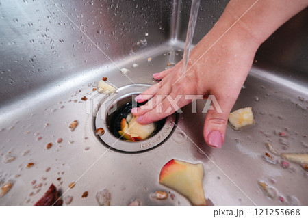 Removing food scraps from a kitchen sink with a garbage disposer and running water. 121255668
