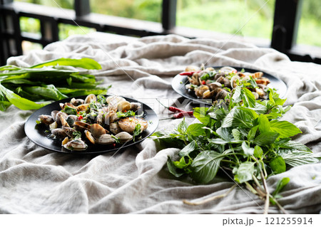 Clams and mussels garnished with herbs and garlic are served on plates on a rustic table. Clams and mussels garnished with herbs and garlic are served on plates on a rustic table. 121255914