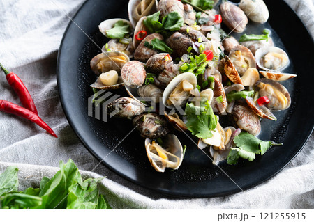 A vibrant plate of clams and mussels mixed with garlic and fresh herbs showcases delicious seafood. 121255915