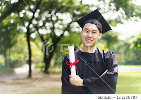 Male student in graduation gown has an excited and delighted expression as he receive his diploma upon graduating from university. An Asian student feel proud about academic achievement. Male student in graduation gown has an excited and delighted expression as he receive his diploma upon graduating from university. An Asian student feel proud about academic achievement. 121256787