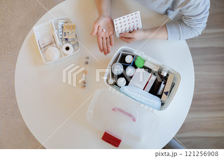 Female hands hold a pink round pill. The woman is going to take medicine for headaches, stomach pain 121256908