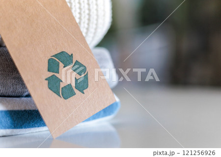 Knitted warm clothes neatly folded heap with craft tag recycling material circle arrow closeup 121256926