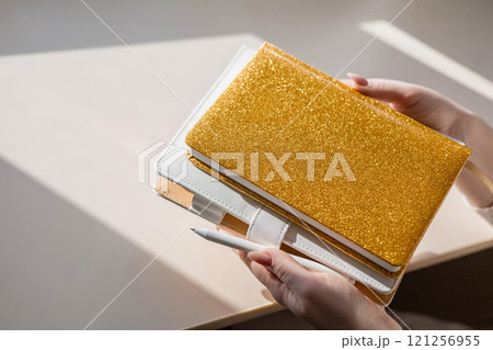 Gold colored diary, pen on bright background. New year planning concept. Gold colored diary, pen on bright background. New year planning concept. 121256955