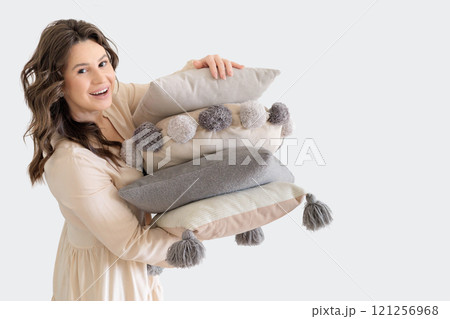 Beautiful European woman in beige suit holds Stack of decorative stylish pillows. White background. Beautiful European woman in beige suit holds Stack of decorative stylish pillows. White background. 121256968