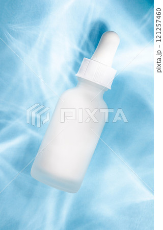 A frosted white dropper bottle on a pastel blue background 121257460