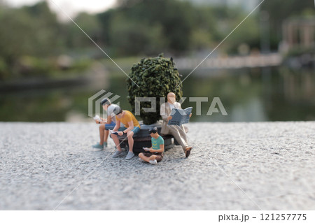 Miniature People Relaxing in Scenic Park Setting 121257775