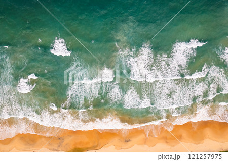 Top view beach with waves crashing on sandy shore,Beautiful waves sea surface in summer seascape background,Amazing beach colorful water background 121257975