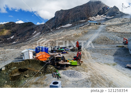 Construction site with heavy machinery and mountain in background 121258354