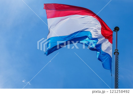 Waving flag of Luxembourg in front of blue sky on a sunny day Waving flag of Luxembourg in front of blue sky on a sunny day 121258492