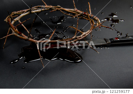 A crown of thorns with blood and knife on a dark background. Conceptual photo to use in the design. A wreath of branches with thorns with blood A crown of thorns with blood and knife on a dark background. Conceptual photo to use in the design. A wreath of branches with thorns with blood 121259177
