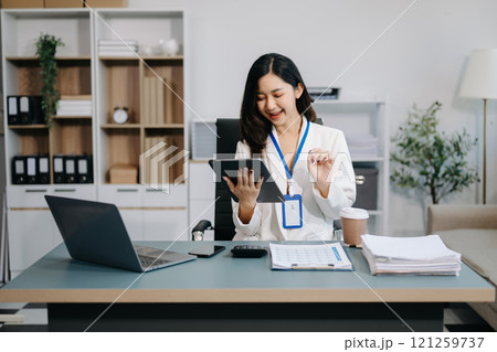 Confident business expert attractive smiling young woman typing laptop and holding digital tablet on desk in office. Confident business expert attractive smiling young woman typing laptop and holding digital tablet on desk in office. 121259737