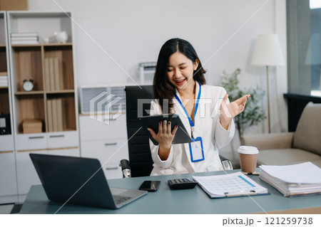 Asian Businesswoman Analyzing Finance on Tablet and Laptop at modern Office Desk Asian Businesswoman Analyzing Finance on Tablet and Laptop at modern Office Desk 121259738