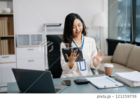 Asian Businesswoman Analyzing Finance on Tablet and Laptop at modern Office Desk Asian Businesswoman Analyzing Finance on Tablet and Laptop at modern Office Desk 121259739