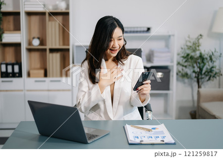 Beautiful Asian business woman typing laptop and tablet Placed at the table at the office 121259817