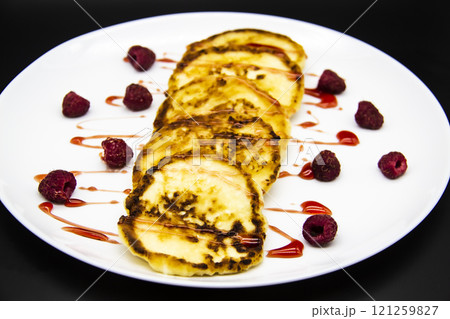 Ukrainian cottage cheese fritters, syrniki with jam on white plate. Cheese pancakes with raspberry without GMO. Delicious breakfast food at the morning. 121259827