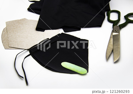 Preparation for sewing a black mask in quarantine at home against white background. Black fabric, blanks for masks, scissors and the soap Preparation for sewing a black mask in quarantine at home against white background. Black fabric, blanks for masks, scissors and the soap 121260293