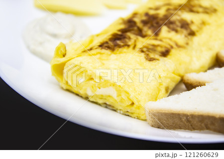 Amazing breakfast with tasty omelet, tomatoes, cheese, bread and sauce on the white plate. Delicious omelet made like rolle, other ingredients. Tasty and diet food. Healthy meal for breakfast or lunch Amazing breakfast with tasty omelet, tomatoes, cheese, bread and sauce on the white plate. Delicious omelet made like rolle, other ingredients. Tasty and diet food. Healthy meal for breakfast or lunch 121260629