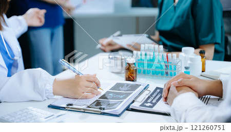 Medical team having a meeting with doctors in white lab coats and surgical scrubs seated Medical team having a meeting with doctors in white lab coats and surgical scrubs seated 121260751