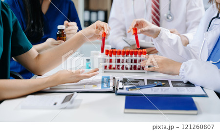 Medical team having a meeting with doctors in white lab coats and surgical scrubs seated 121260807