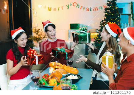 drinks and conversation, people celebrating together at Merry Christmas and Happy New Year. Friends are happy and celebrating with food, wine and friendship of love and gift exchange at the event. 121261170