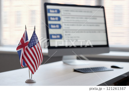 Close up on small national flags of USA and Great Britain standing on teachers desk in classroom of English language school, copy space Close up on small national flags of USA and Great Britain standing on teachers desk in classroom of English language school, copy space 121261387