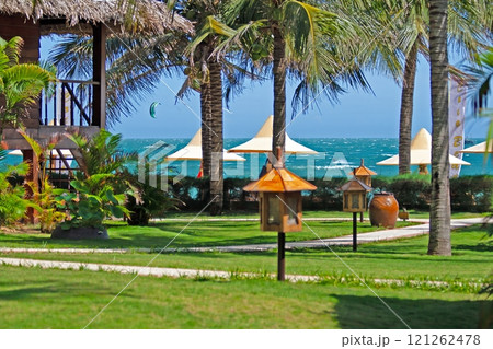 Tropical beach resort with palm trees, ocean view, and vibrant green lawn in Vietnam Tropical beach resort with palm trees, ocean view, and vibrant green lawn in Vietnam 121262478