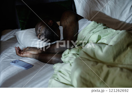 African American man enjoying rest in bed at night, he sleeping in bed with fresh washed linen African American man enjoying rest in bed at night, he sleeping in bed with fresh washed linen 121262692