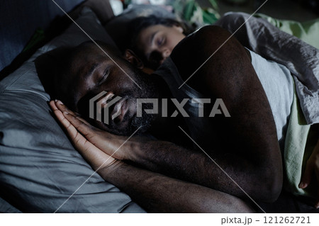 Medium close up of African American man sleeping easy while his wife hugging him Medium close up of African American man sleeping easy while his wife hugging him 121262721