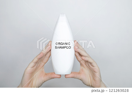 Female hands holding a bottle with the words - organic shampoo. Concept of safe composition and ingredients of environmentally friendly cosmetics and detergents Female hands holding a bottle with the words - organic shampoo. Concept of safe composition and ingredients of environmentally friendly cosmetics and detergents 121263028