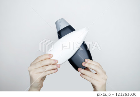 Female hands holding a can of shampoo with a blank label. White background, space for text. Composition of shampoo or conditioner 121263030
