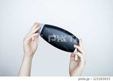 Female hands holding a can of shampoo, where it is written no sls, sls free. The concept of safe composition of shampoo without aggressive components Female hands holding a can of shampoo, where it is written no sls, sls free. The concept of safe composition of shampoo without aggressive components 121263035