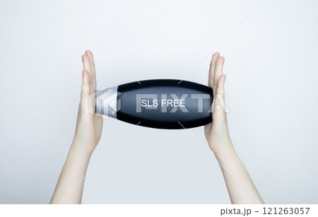 Female hands holding a can of shampoo, where it is written no sls, sls free. The concept of safe composition of shampoo without aggressive components 121263057