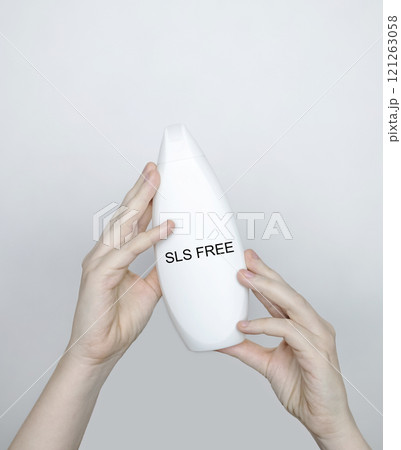 Female hands holding a can of shampoo, where it is written no sls, sls free. The concept of safe composition of shampoo without aggressive components Female hands holding a can of shampoo, where it is written no sls, sls free. The concept of safe composition of shampoo without aggressive components 121263058